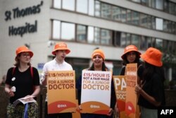 Para pengunjuk rasa memegang plakat British Medical Association (BMA) yang menyerukan agar memperoleh gaji yang lebih baik di luar Rumah Sakit St Thomas di pusat kota London, 27 Juni 2024, seminggu sebelum pemilihan umum 4 Juli 2024. (HENRY NICHOLLS / AFP)