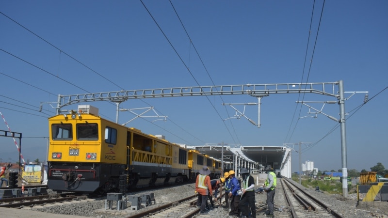 Sebuah kereta api melintas saat para pekerja yang sedang memeriksa sistem elektronik kereta api cepat buatan China yang menghubungkan Ibu Kota Jakarta dengan Bandung, di stasiun Tegalluar, Bandung, Jawa Barat, 15 Mei 2023. (TIMUR MATAHARI/AFP)