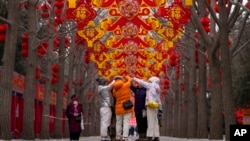 Residents take a selfie near trees decorated with red lanterns and decorations ahead of the Chinese Lunar New Year at Ditan Park in Beijing, Feb. 4, 2024. Chinese will celebrate Lunar New Year on Feb. 10 this year.