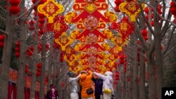 Residentes se toman una selfie cerca de árboles decorados con linternas rojas y adornos antes del Año Nuevo Lunar chino en el Parque Ditan en Beijing, el 4 de febrero de 2024.