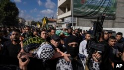 FILE - Mourners carry the bodies of three Palestinians draped in the Hamas and Islamic Jihad militant group flags during their funeral in the Jenin refugee camp, West Bank, Nov. 17, 2023.