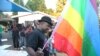 FILE - Samba Chesterfield, Director of Gays and Lesbians Association of Zimbabwe, prepares to hoist their official flag alongside the Zimbabwean flag during during an event in Harare, Zimbabwe on Saturday, May, 19, 2012.