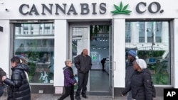 FILE - People pass by a cannabis shop in midtown Manhattan in New York on March 19, 2024. 