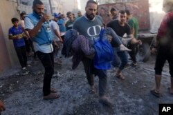 Palestinians evacuate survivors after Israeli airstrikes on buildings in Deir al Balah, Gaza Strip, Nov. 7, 2023.