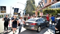 Pickets carry signs outside Disney studios, July 20, 2023, in Burbank, Calif. The actors strike comes more than two months after screenwriters began striking in their bid to get better pay and working conditions.