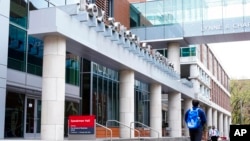 FILE - People walk past the Fox School of Business on the Temple University campus in Philadelphia, April 16, 2021.