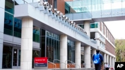 FILE - People walk past the Fox School of Business on the Temple University campus in Philadelphia, April 16, 2021. 