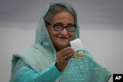 FILE - Bangladesh Prime Minister Sheikh Hasina shows her ballot paper as she casts her vote in Dhaka, Jan. 7, 2024.