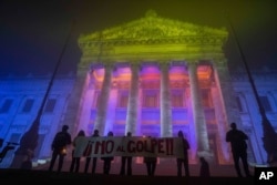 La gente sostiene un cartel que dice "No al golpe", en conmemoración del 50 aniversario del golpe militar de 1973, frente al Palacio Legislativo en Montevideo, Uruguay, el martes 27 de junio de 2023. (Foto AP/Matilde Campodonico)
