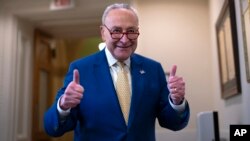 Senate Majority Leader Chuck Schumer, D-N.Y., signals success to reporters after the Senate passed a foreign aid package, at the Capitol in Washington, Feb. 13, 2024.