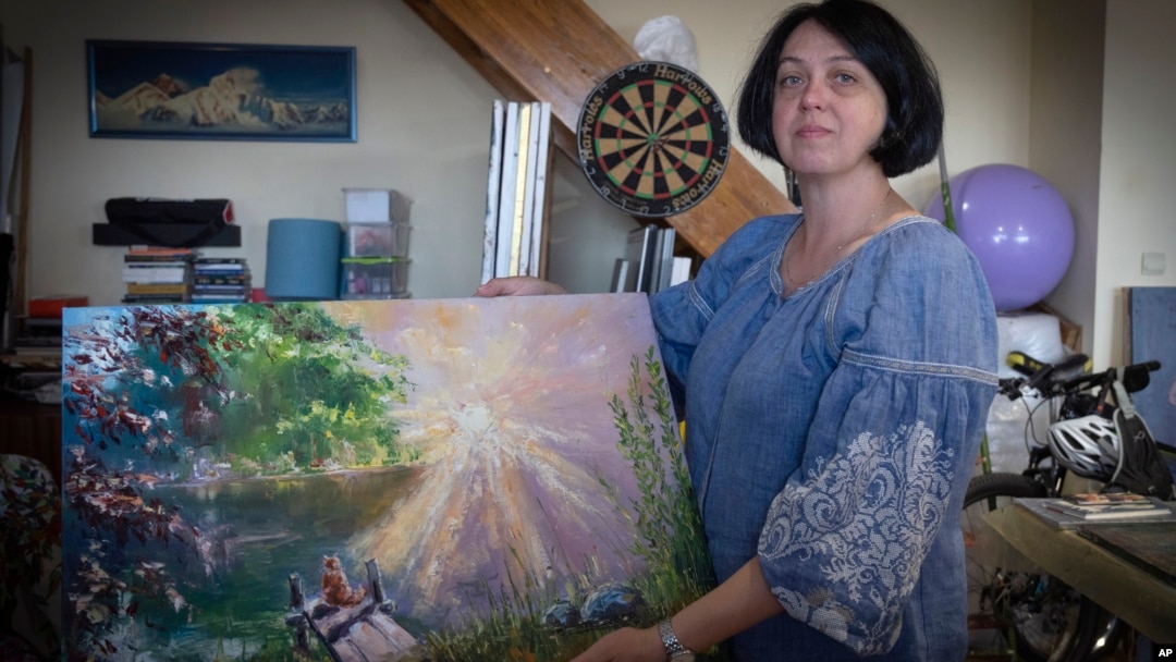 Oksana Kordina sostiene su pintura que creó para conmemorar a su esposo, un soldado que murió en una batalla con las tropas rusas, en un estudio de arte en Kiev, Ucrania, el sábado 3 de junio de 2023.