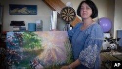 Oksana Kordina sostiene su pintura que creó para conmemorar a su esposo, un soldado que murió en una batalla con las tropas rusas, en un estudio de arte en Kiev, Ucrania, el sábado 3 de junio de 2023.