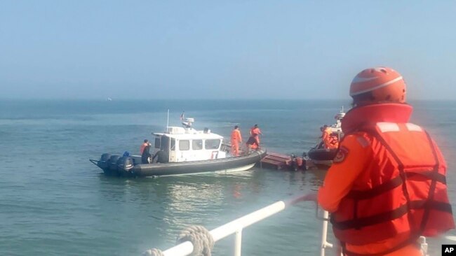 In this handout photograph provided by Taiwan Coast Guard Administration, Taiwanese coast guards inspect a vessel that capsized during a chase off the coast of Kinmen archipelago in Taiwan, Feb. 14, 2024.