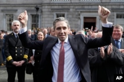 Perdana Menteri Irlandia yang baru, Simon Harris, memberi isyarat saat dia mendapat tepuk tangan dari sesama anggota parlemen di luar Leinster House, di Dublin, Irlandia, 9 April 2024. (Foto: AP)