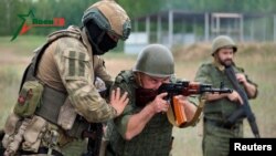 A fighter from Russian Wagner mercenary group conducts training for Belarusian soldiers on a range near the town of Osipovichi, Belarus July 14, 2023 in this still image taken from handout video.