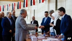 Syrian Prime Minister Hussein Arnous, center left, and Syrian Foreign Minister Faisal Mekdad, left, arrive to a polling station to cast their votes during the Syrian parliamentary election in Damascus, July 15, 2024.