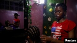 FILE - Blessing Samuel, a 27-year old hairstylist, braids a woman's hair at her beauty salon in Lagos, Nigeria October 10, 2022. 