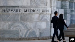 FILE - Pedestrians walk towards the Harvard Medical School, Aug. 18, 2022, in Boston. 