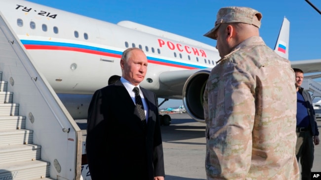 FILE - Russian President Vladimir Putin listens the report of Col. Gen. Sergei Surovikin, Russian Commander in Syria, at the Hemeimeem air base in Syria, on Dec. 11, 2017.