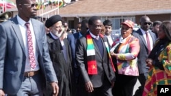 Iran's President Ebrahim Raisi waves while next to Zimbabwean President Emmerson Mnangagwa upon his arrival at Robert Mugabe International Airport in Harare, Zimbabwe, July 13, 2023.