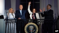 First lady Jill Biden and second gentleman Douglass Emhoff watch as President Joe Biden raises the hand of Vice President Kamala Harris as they view Independence Day fireworks from the balcony of the White House, July 4, 2024, in Washington. 