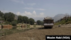 A houseboat that usually floats on the water is marooned on the riverbed after a heat wave decreased the water level of the Jhelum River on Sept. 22, 2023.