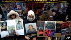 FILE - Women sit holding pictures of victims and posters with messages of protest during a demonstration against China's brutal crackdown on Uyghurs, in front of the Chinese Consulate in Istanbul, Turkey, Nov. 30, 2022.