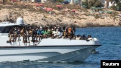 Migran tiba dengan kapal Penjaga Pantai Italia setelah diselamatkan di laut, di pulau Lampedusa, Sisilia, Italia, 15 September 2023. (REUTERS/Yara Nardi)