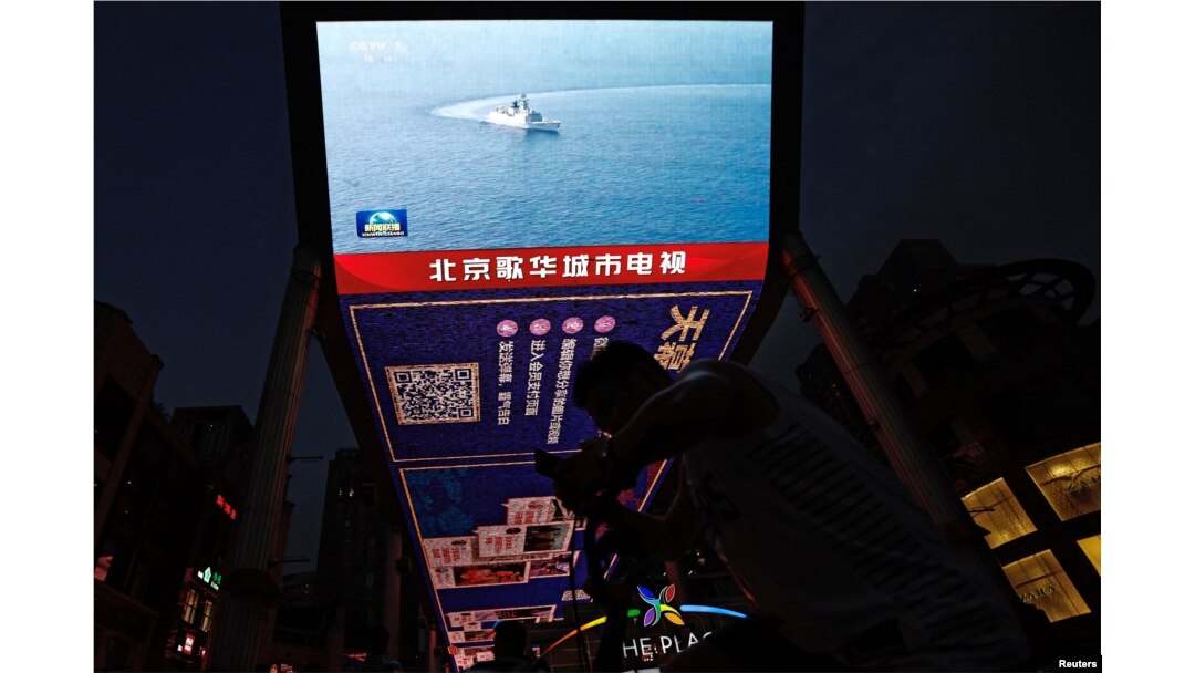 FILE - A screen broadcasts news footage of a Navy Force vessel taking part in military drills by the Eastern Theatre Command of China's People's Liberation Army around Taiwan, in a shopping area in Beijing, Aug. 19, 2023.