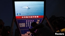 资料照片：一个大型屏幕在播放中国军队东部战区的一艘军舰在台湾周围进行军事演练的新闻画面。(2023年8月19日)