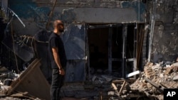 Dmytro Ihnatenko, owner of the destroyed Ria Pizza, stands beside a wide hole left from an Iskander missile that hit his business in June, in Kramatorsk, Ukraine, Sept. 13, 2023. 