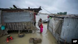 2일 인도 아삼 주 북동부 모리가온 지역 실두비의 물에 잠긴 집 근처에서 어린아이가 홍수를 헤치고 걸어가고 있다.