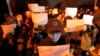 FILE - Protesters hold up blank papers and chant slogans as they march in protest in Beijing, Nov. 27, 2022.