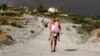 A man carries a child as they leave an area where a forest fire burns, on the island of Rhodes, Greece, July 22, 2023. 