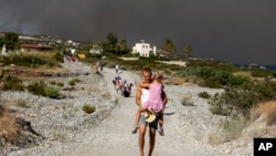 Homem com uma cirança foge dos incêncios na ilha de Rhodes, Grécia, 22 Julho 2023