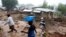People walk past homes damaged by Cyclone Freddy in Chilobwe, Malawi, March 17, 2023.