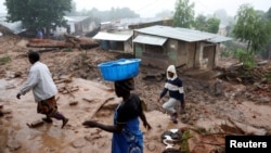 FILE - People walk past houses damaged in the aftermath of Tropical Cyclone Freddy in Blantyre, Malawi, on March 17, 2023. Meteorologists and officials in Malawi warned the nation on Dec. 13, 2024, that Tropical Cyclone Chido could bring similar heavy rain and flooding.