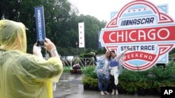 Fans take pictures in the rain before a NASCAR Cup Series auto race at the Grant Park 220, July 2, 2023, in Chicago. 