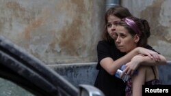 Local residents react at the site of a residential building hit by a Russian missile in Lviv, Ukraine, July 6, 2023.