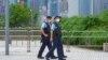 FILE - Police officers patrol outside a train station in Hong Kong, June 30, 2022.
