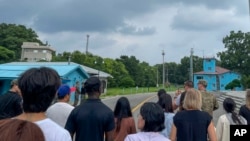 Tourists stand near a border station at Panmunjom in the Demilitarized Zone in Paju, South Korea, July 18, 2023. Not long after this photo was taken, Travis King, a U.S. soldier, fourth left in dark blue shirt, bolted across the border.