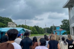 Tourists stand near a border station at Panmunjom in the Demilitarized Zone in Paju, South Korea, July 18, 2023. Not long after this photo was taken, Travis King, a U.S. soldier, fourth left, in dark blue shirt, bolted across the border.