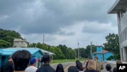 Tourists stand near a border station at Panmunjom in the Demilitarized Zone in Paju, South Korea, July 18, 2023. Not long after this photo was taken, Travis King, a U.S. soldier, fourth left, in dark blue shirt, bolted across the border.