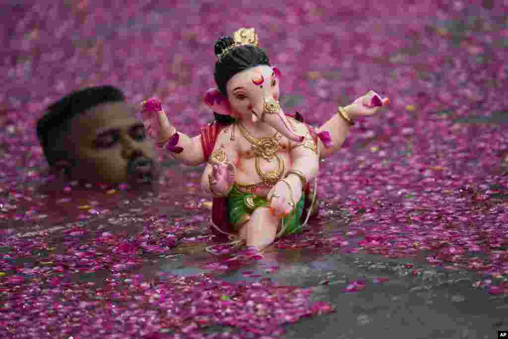 A man prepares to immerse in an artificial pond, an idol of elephant headed Hindu god Ganesha on the second day of ten days long Ganesh Chaturthi festival in Mumbai, India.