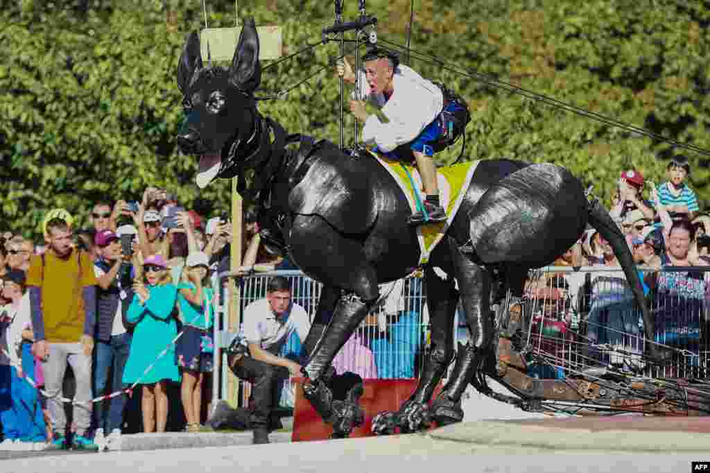 Members of the French street theatre company "Royal de Luxe" perform on Xolo, a giant dog puppet, during the show "Le Bull Machin de Mr Bourgogne" in Nantes, France, Sept. 24, 2023.