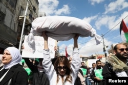 FILE - A demonstrator holds rolled up white cloth during a protest in support of Palestinians in Gaza, amid the ongoing conflict between Israel and Palestinian Islamist group Hamas, in Amman, Jordan, March 15, 2024.
