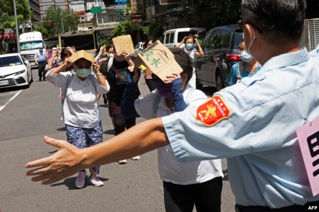 Seorang sukarelawan memandu penduduk setempat berlindung selama Latihan Serangan Udara Wanan, serangan udara sipil yang diadakan pada latihan militer tahunan Han Kuang, di Taipei, 24 Juli 2023. (Jameson WU / AFP)