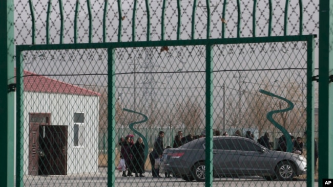 FILE - Residents line up inside the Artux City Vocational Skills Education Training Service Center, which had been revealed by leaked documents to be a forced indoctrination camp in western China's Xinjiang region, Dec. 3, 2018.