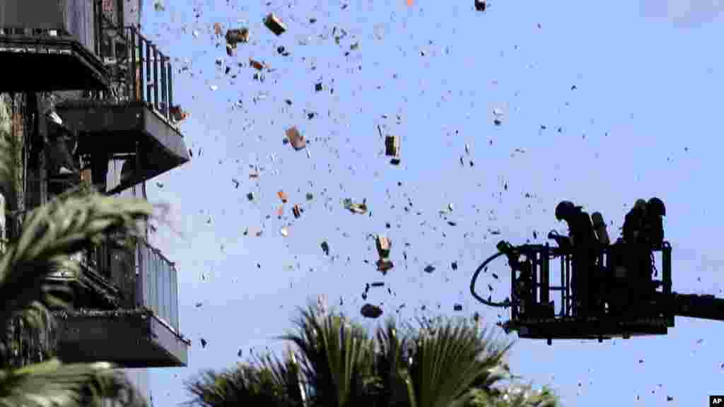 Debris falls on firefighters as they work at a burned block building in Valencia, Spain. (AP Photo/Alberto Saiz)