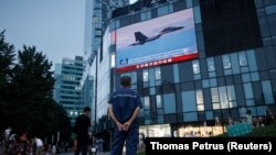 Seorang pria menonton siaran berita CCTV yang menunjukkan jet tempur di dekat Taiwan oleh Komando Teater Timur Tentara Pembebasan Rakyat China (PLA), di sebuah pusat perbelanjaan di Beijing, China, 3 Agustus 2022. (Foto: REUTERS/Thomas Petrus)